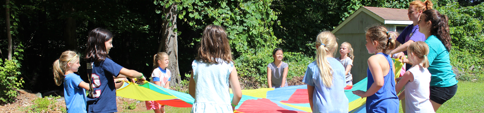  group of girls in a circle with counselors playing with the parachute 