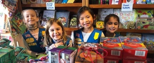 Four smiling Girl Scout Daisies at a Girl Scout cookie booth Four smiling Girl Scout Daisies at a Girl Scout cookie booth