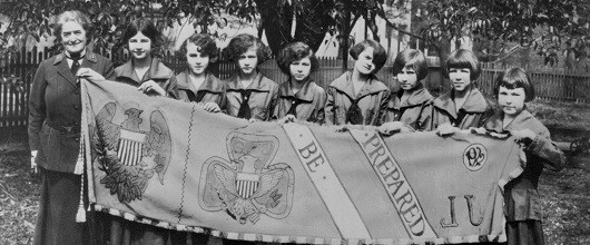 Girl Scouts founder Juliette Gordon Low with eight Girl Scouts holding up a Girl Scout banner