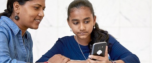 A Girl Scout and volunteer looking at a smart phone