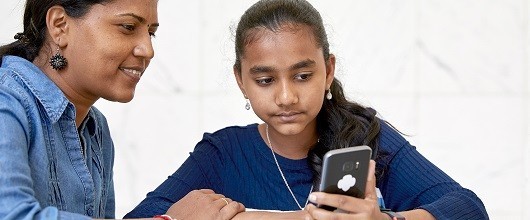 A Girl Scout and volunteer looking at a smart phone A Girl Scout and volunteer looking at a smart phone