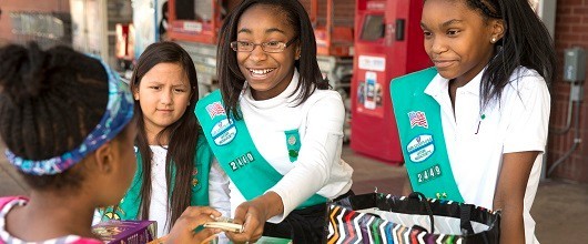 Three Girl Scout Juniors selling Girl Scout Cookies