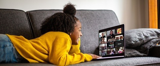 A smiling Girl Scout using a laptop at home on a couch