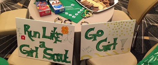 Two cardboard signs with text in green letters: "Run Like a Girl Scout" and "Go Girl!" Two cardboard signs with text in green letters: "Run Like a Girl Scout" and "Go Girl!"