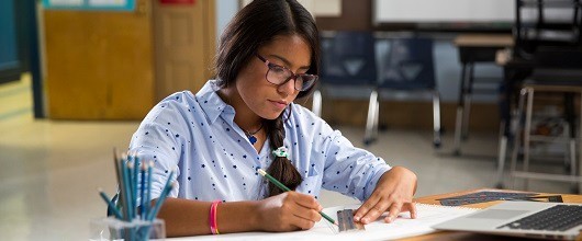 A Girl Scout sitting at a desk writing A Girl Scout sitting at a desk writing