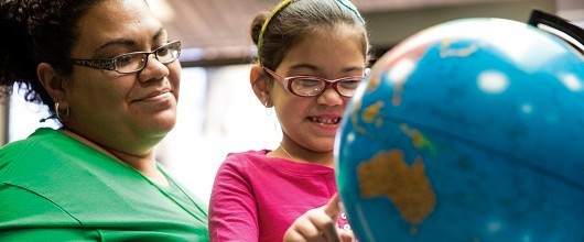 A Girl Scout volunteer with a Girl Scout pointing to a globe