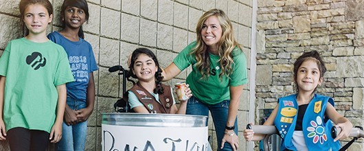 A Girl Scout troop and volunteer at an outdoor event