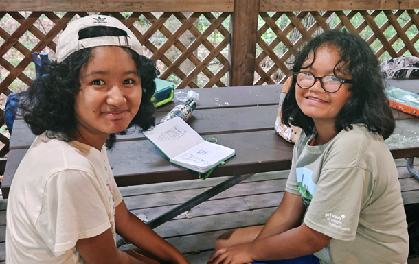 two girls sitting at a picnic table