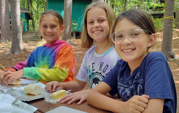 three girls at camp preparing food