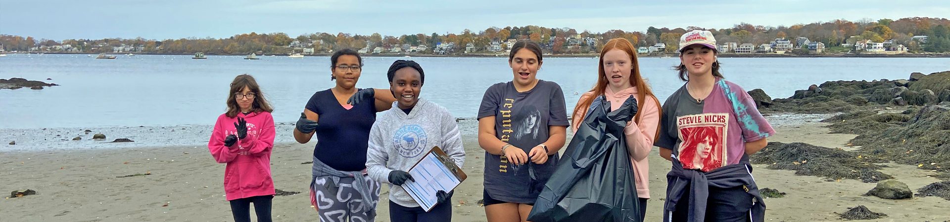  group of girls on the beach picking up trash 