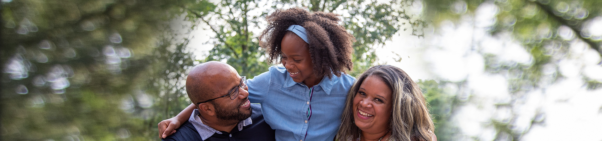  family with mom, dad, and young daughter outside smiling 