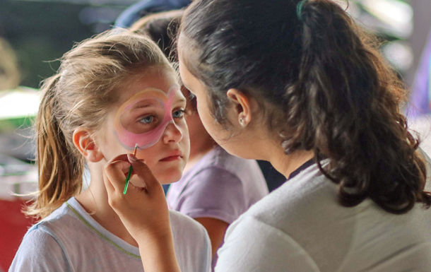 Girl Scout painting a face of prospective Girl Scout.