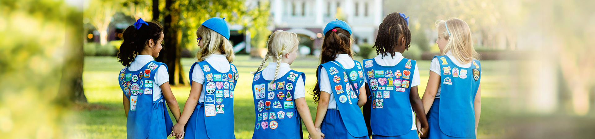  Group of Daisy Girl Scouts facing with their backs to us in uniform  